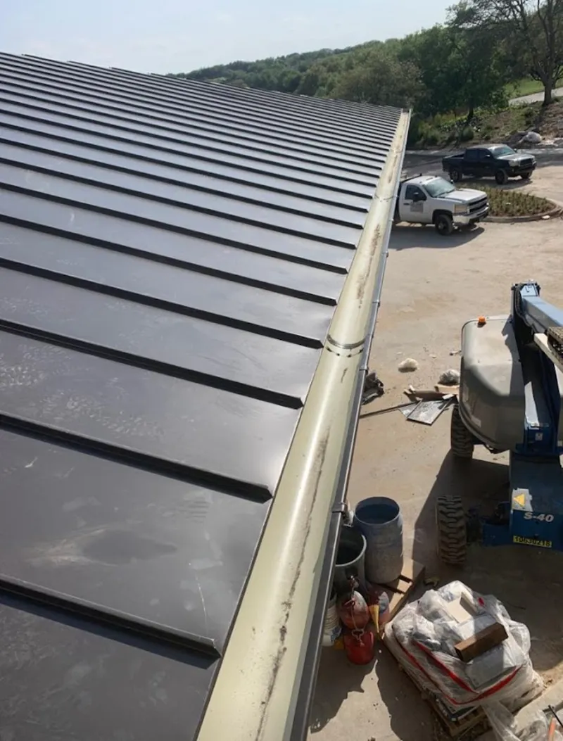 Standing seam panel and gutter detail on a metal roofing jobsite in Elon